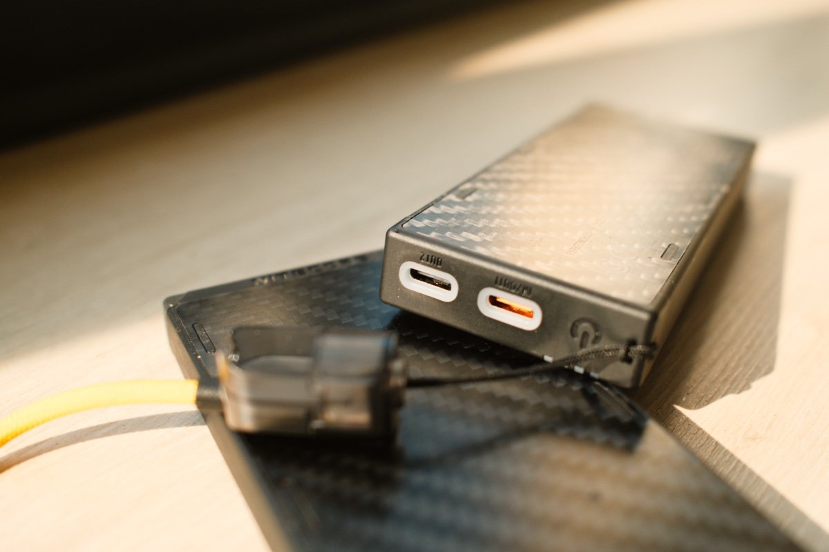 Batterie externe Nitecore NB10000 Gen 4 avec ports USB-C et câble intégré posée sur une surface en carbone