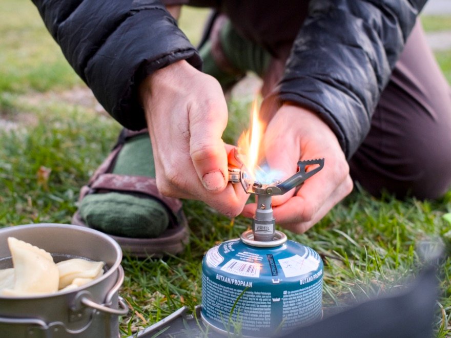 Les meilleurs réchauds pour le bivouac 16 Allumage d’un réchaud à gaz avec un briquet pendant un bivouac, popote en cuisson avec des raviolis