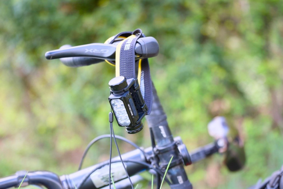 Test & Avis Nitecore HC65 UHE : La lampe frontale ultime pour le bikepacking ? 11 Lampe frontale Nitecore HC65 UHE fixée au bandeau classique suspendue au guidon d’un vélo de gravel