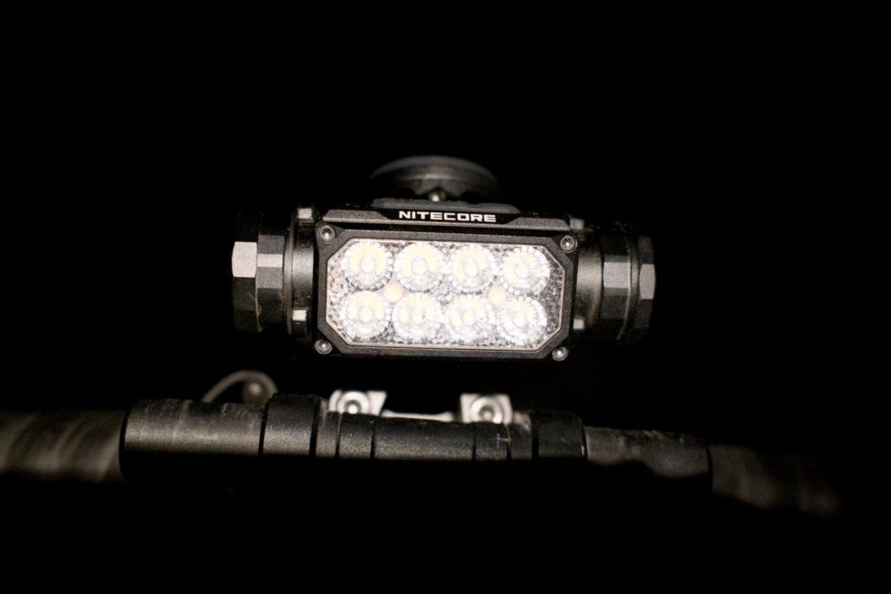 Test & Avis Nitecore HC65 UHE : La lampe frontale ultime pour le bikepacking ? 12 Lampe frontale Nitecore HC65 UHE allumée de nuit sur le guidon d’un vélo gravel pendant un test nocturne