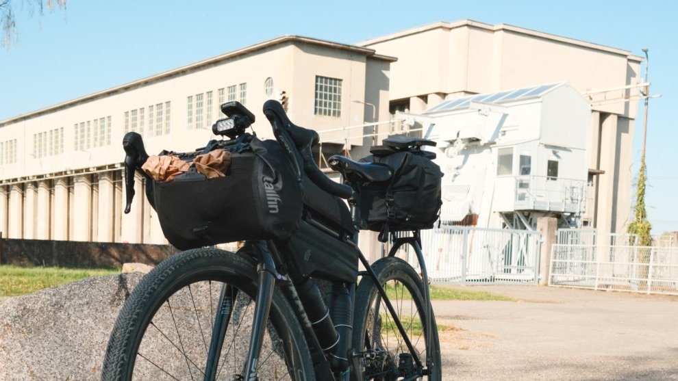 Vélo gravel équipé de la sacoche de guidon Tailfin Bar Bag devant un bâtiment industriel