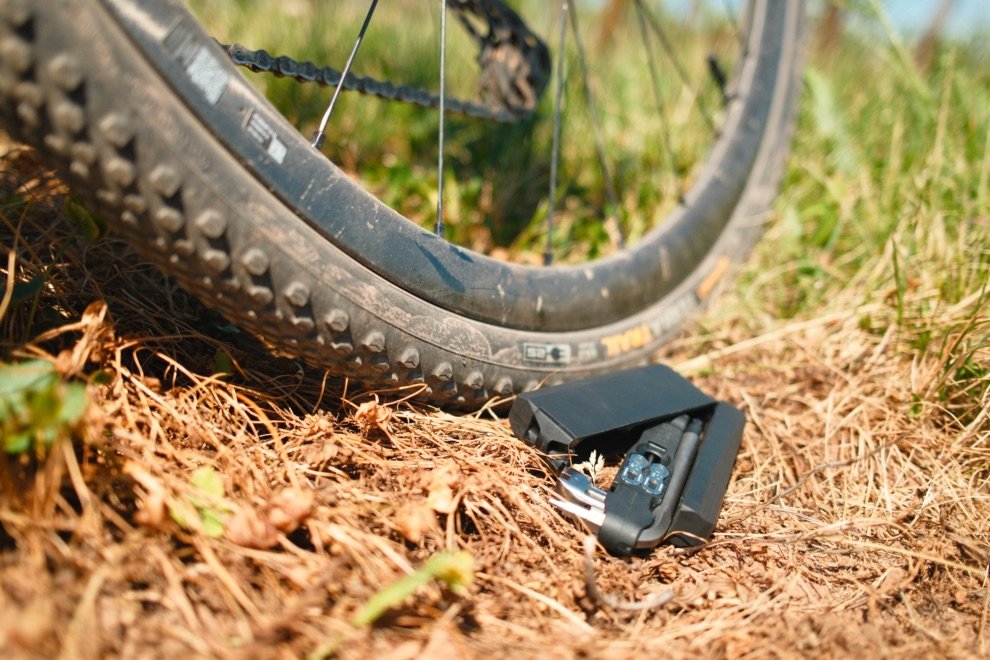 Test du multi-outil vélo DaySaver : Essential8 + Coworking6TL = le combo parfait ? 9 Multi-outil vélo DaySaver Essential8 + Coworking6TL posé au sol près d’un pneu gravel, idéal pour les réparations en pleine sortie