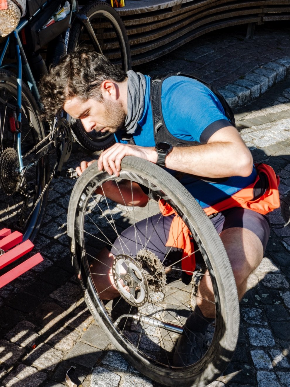 Test du multi-outil vélo DaySaver : Essential8 + Coworking6TL = le combo parfait ? 17 Cycliste en pleine réparation de roue pendant un test terrain du multi-outil DaySaver