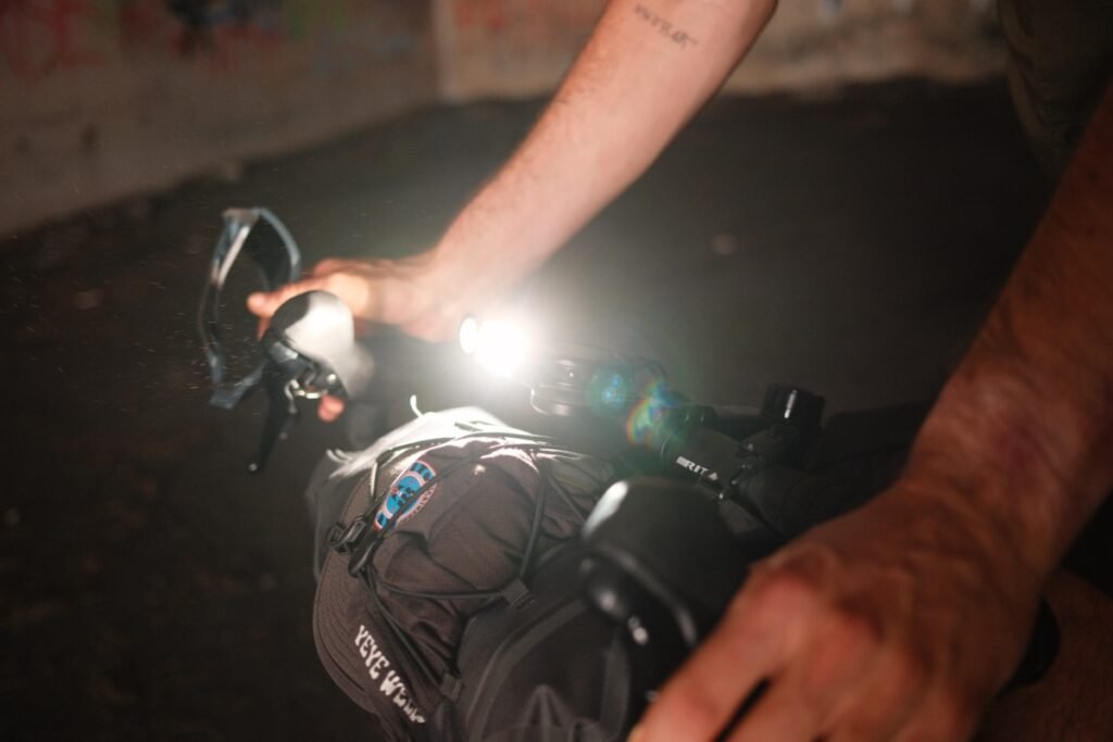 Lampe frontale Stoots Opalo 3 éclairant un vélo lors d’une sortie nocturne, utilisée pour illustrer son autonomie.