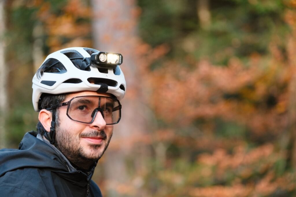 Cycliste portant une lampe frontale Stoots Opalo 3 fixée sur son casque lors d’une sortie en forêt pour du bikepacking.