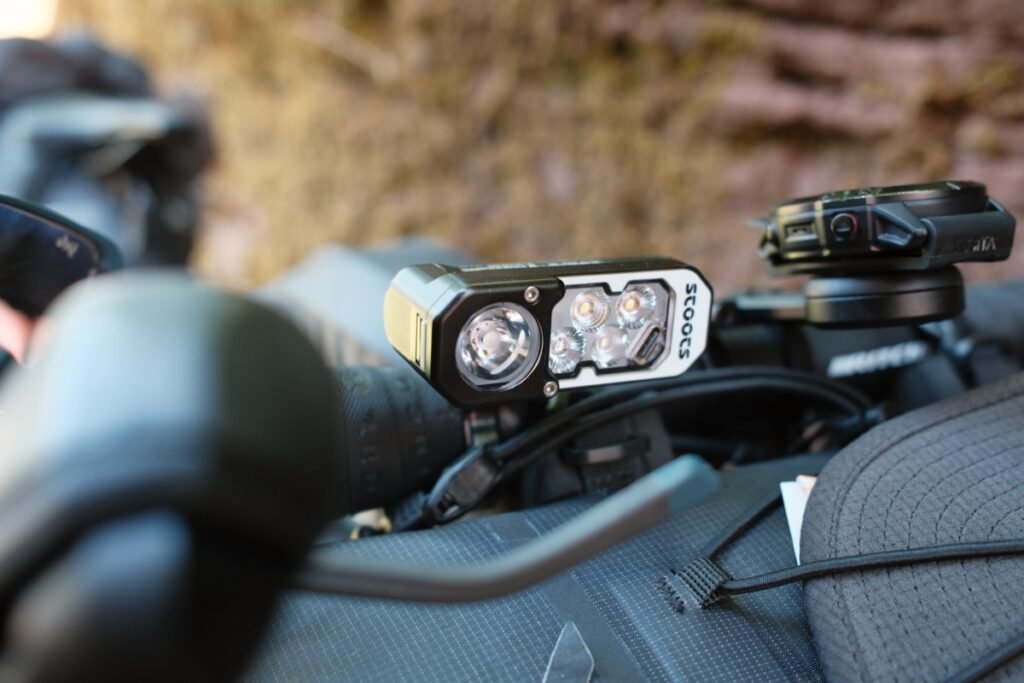 Lampe frontale Stoots Opalo 3 montée sur un support guidon de vélo lors d’une sortie bikepacking.