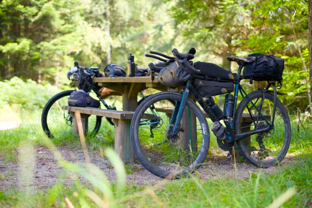 Prolongateur vélo : le guide complet pour bien choisir 11 Vélo de bikepacking chargé équipé de prolongateurs et d'une sacoche de guidon, posé en forêt