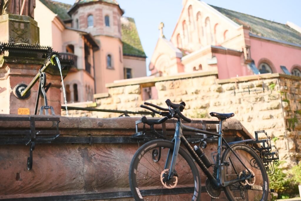 Prolongateur vélo : le guide complet pour bien choisir 6 Vélo équipé de prolongateurs appuyé contre une fontaine en pierre dans un village d'Alsace