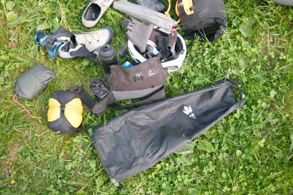 Les meilleures sacoches de guidon bikepacking : sélection et conseils 19 Sacoche de guidon au format tube posée dans l'herbe avec le matériel de bikepacking déballé