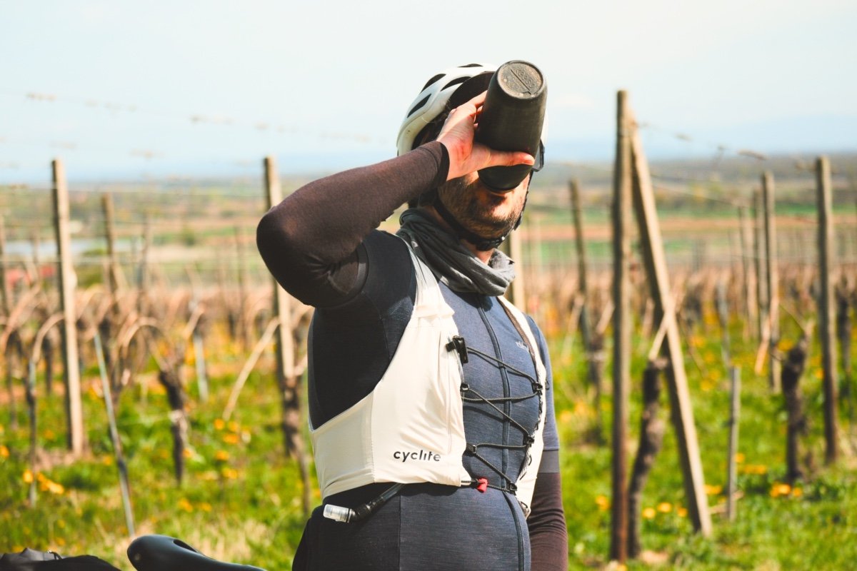 Cycliste buvant un bidon avec le gilet d'hydratation Cyclite Hydration Vest /01 dans les vignes