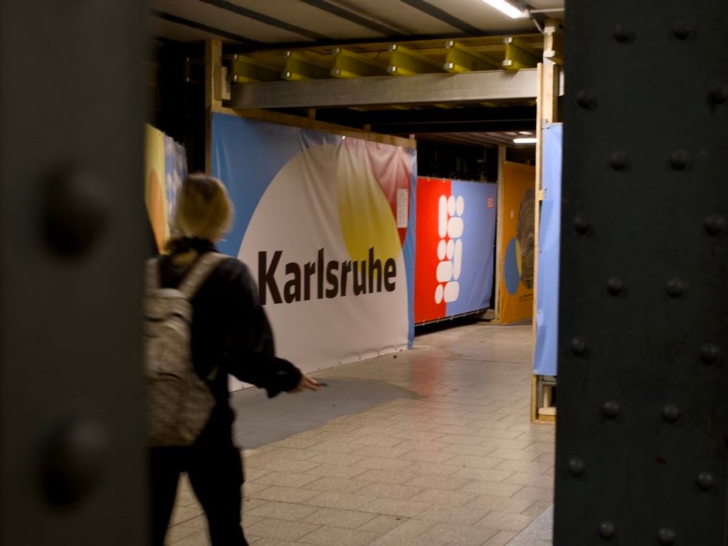 Traversée de la Forêt-Noire en gravel : 544 km en 5 jours, du pneu éclaté à la tente gelée 10 Passage souterrain d'une gare avec une grande bâche colorée portant l'inscription Karlsruhe, à l'arrivée du Schwarzwald-Radweg