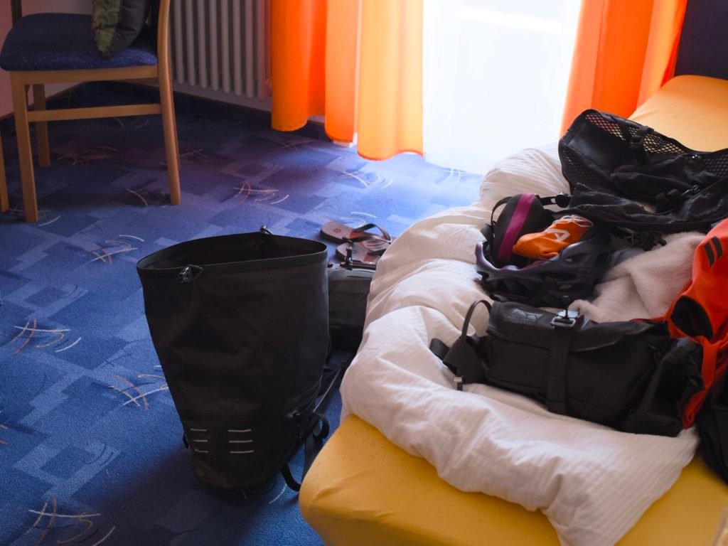 Traversée de la Forêt-Noire en gravel : 544 km en 5 jours, du pneu éclaté à la tente gelée 8 Sacoches de bikepacking vidées dans une chambre d'hôtel, avec une sacoche de selle posée sur la moquette et une sacoche de guidon sur le lit, à Baiersbronn en Forêt-Noire