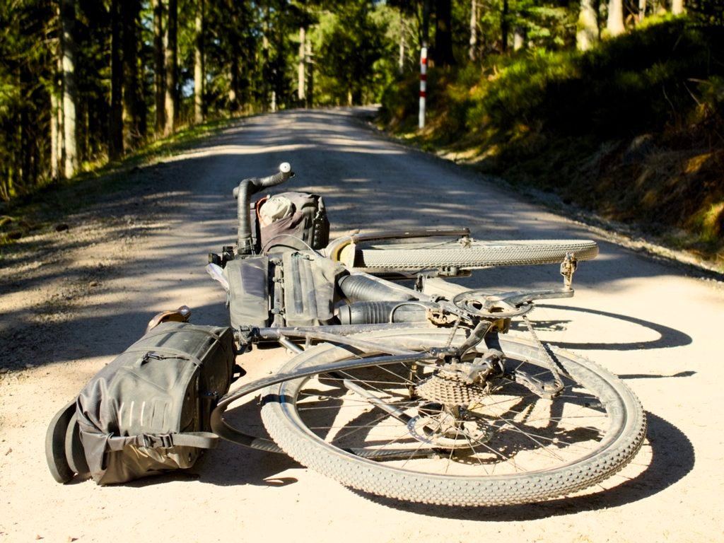Traversée de la Forêt-Noire en gravel : 544 km en 5 jours, du pneu éclaté à la tente gelée 11 Gravel chargé de ses sacoches de bikepacking, couché sur un large chemin forestier en gravier clair, cassette et dérailleur arrière visibles en plein soleil