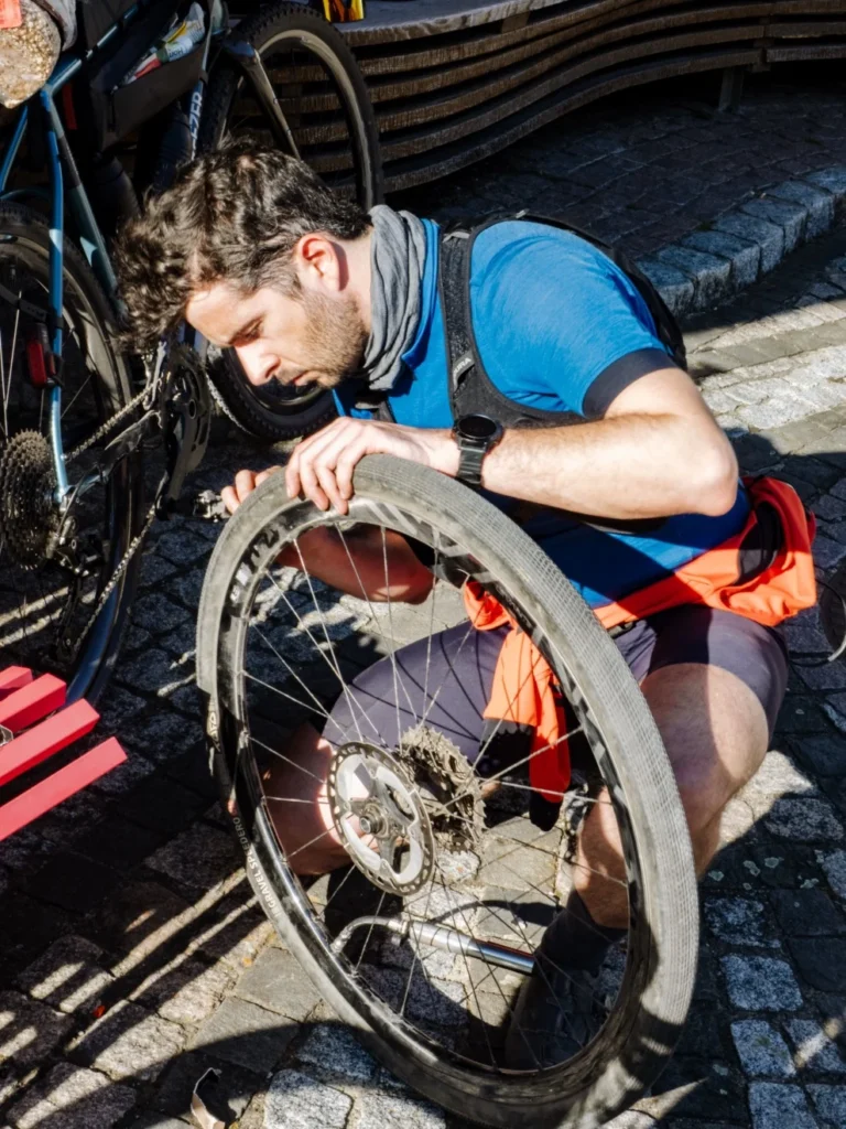 Traversée de la Forêt-Noire en gravel : 544 km en 5 jours, du pneu éclaté à la tente gelée 4 Cycliste accroupi sur des pavés, en train de démonter le pneu Tufo Speedero de la roue arrière de son gravel pendant la traversée de la Forêt-Noire