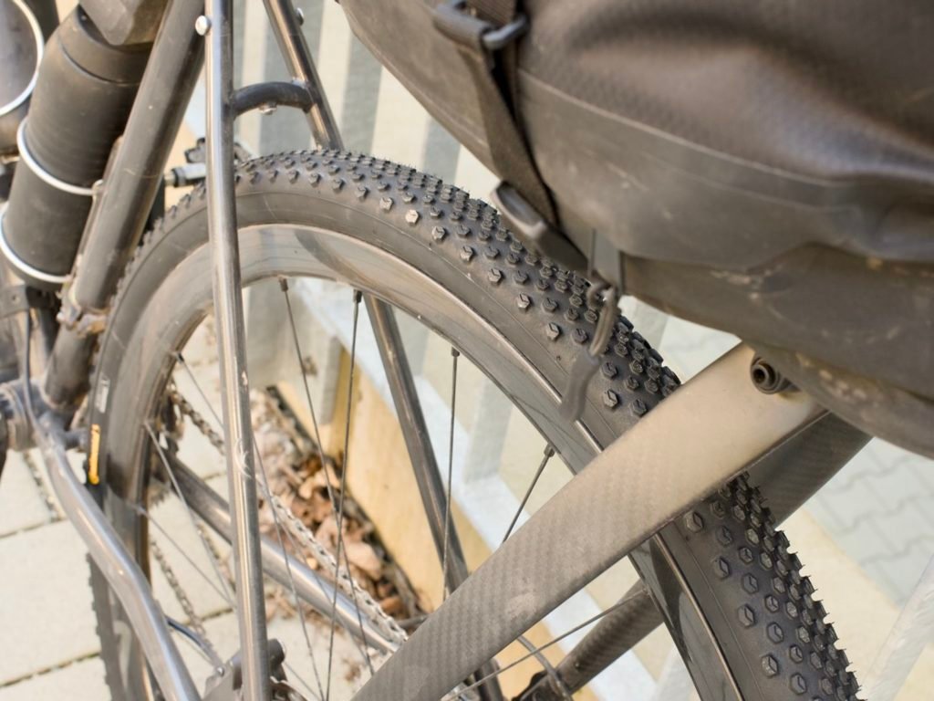 Traversée de la Forêt-Noire en gravel : 544 km en 5 jours, du pneu éclaté à la tente gelée 5 Gros plan sur la roue arrière d'un gravel chargé, avec un pneu à crampons neuf tout juste monté, une sacoche de selle et un second pneu replié fixé au vélo