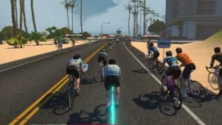 Sortie de groupe sur Zwift au bord de la mer à Watopia, avec l’avatar au premier plan sur le Tron bike aux roues lumineuses