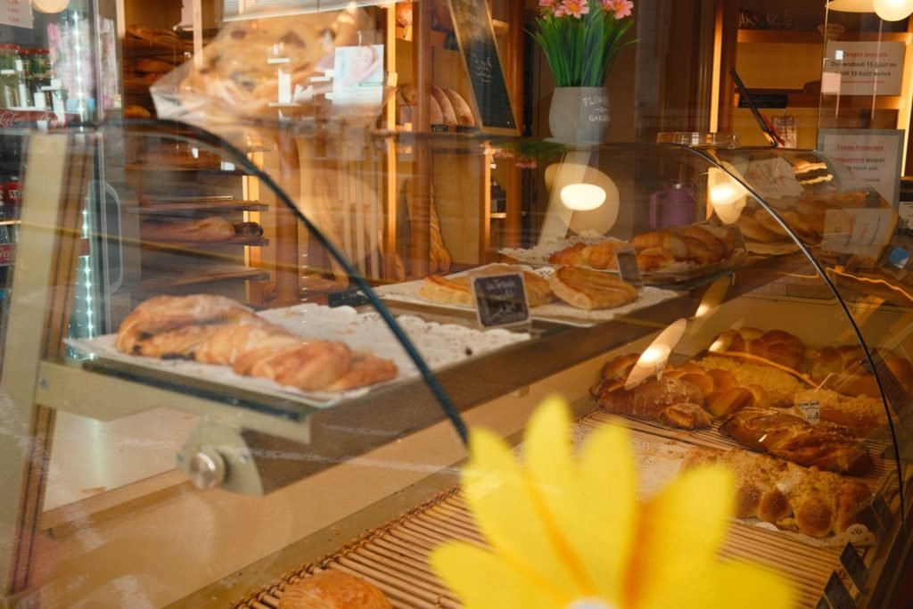 Vitrine d'une boulangerie garnie de viennoiseries et de brioches tressées, lors d'un arrêt ravitaillement pendant un voyage à vélo.